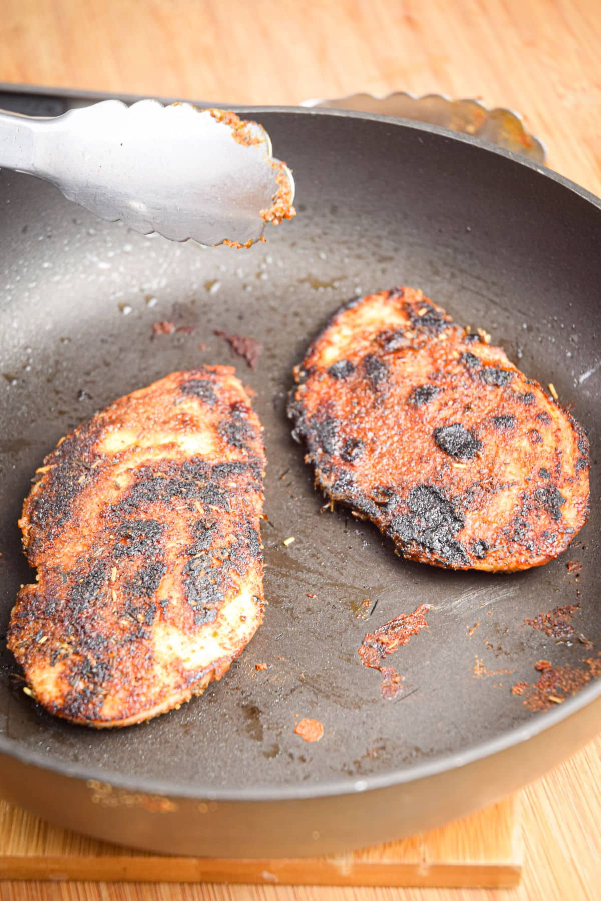 Blackened chicken breasts in pan.