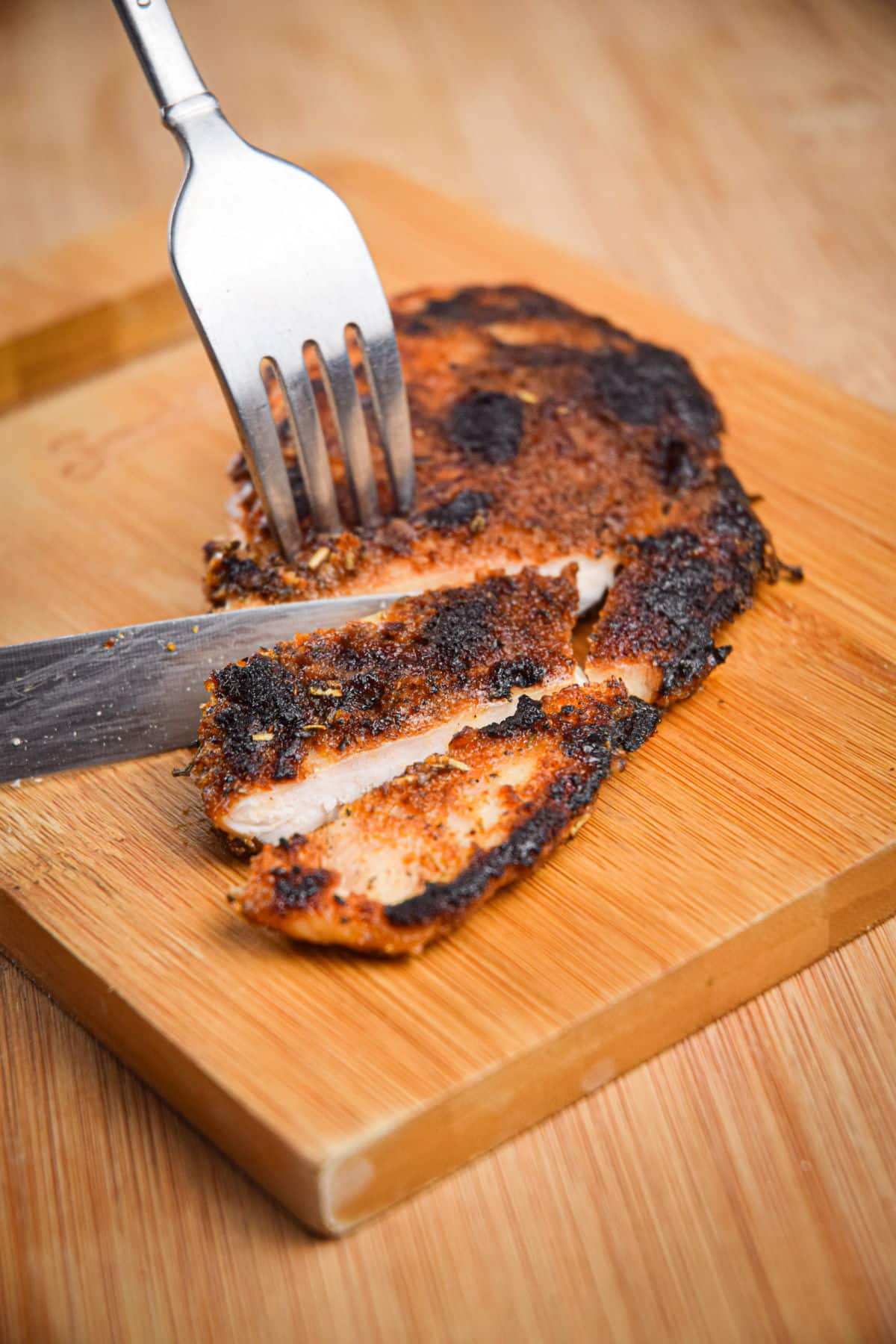 Blackened chicken breast on cutting board.