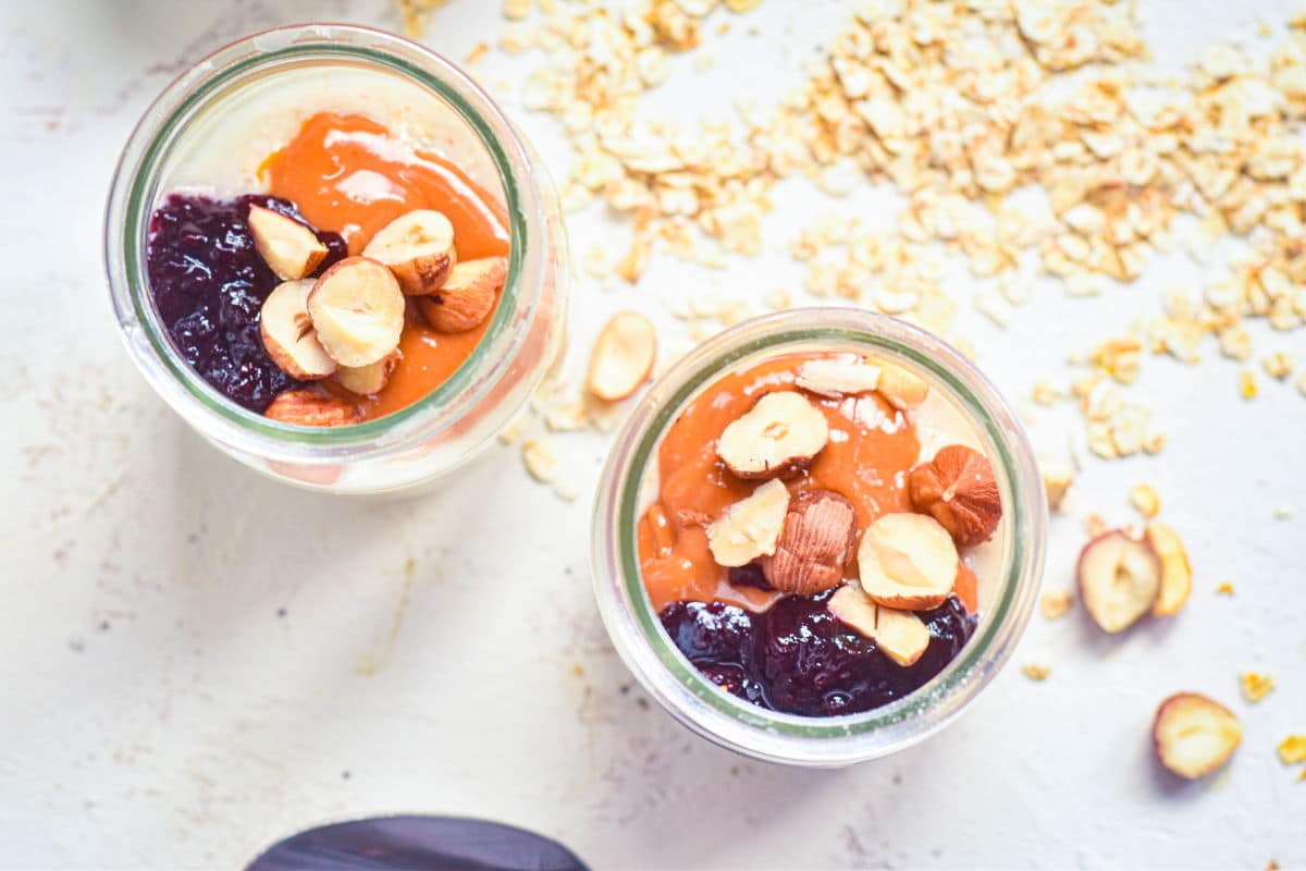 Porridge shots with peanut butter and jam topping, white background.