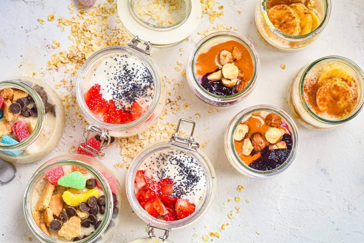 Oatmeal porridge jars with various toppings on white background.