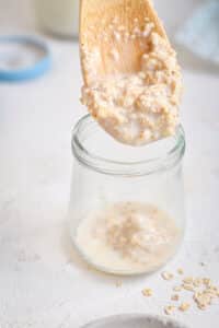 Oatmeal on a wooden spoon and in small jar.
