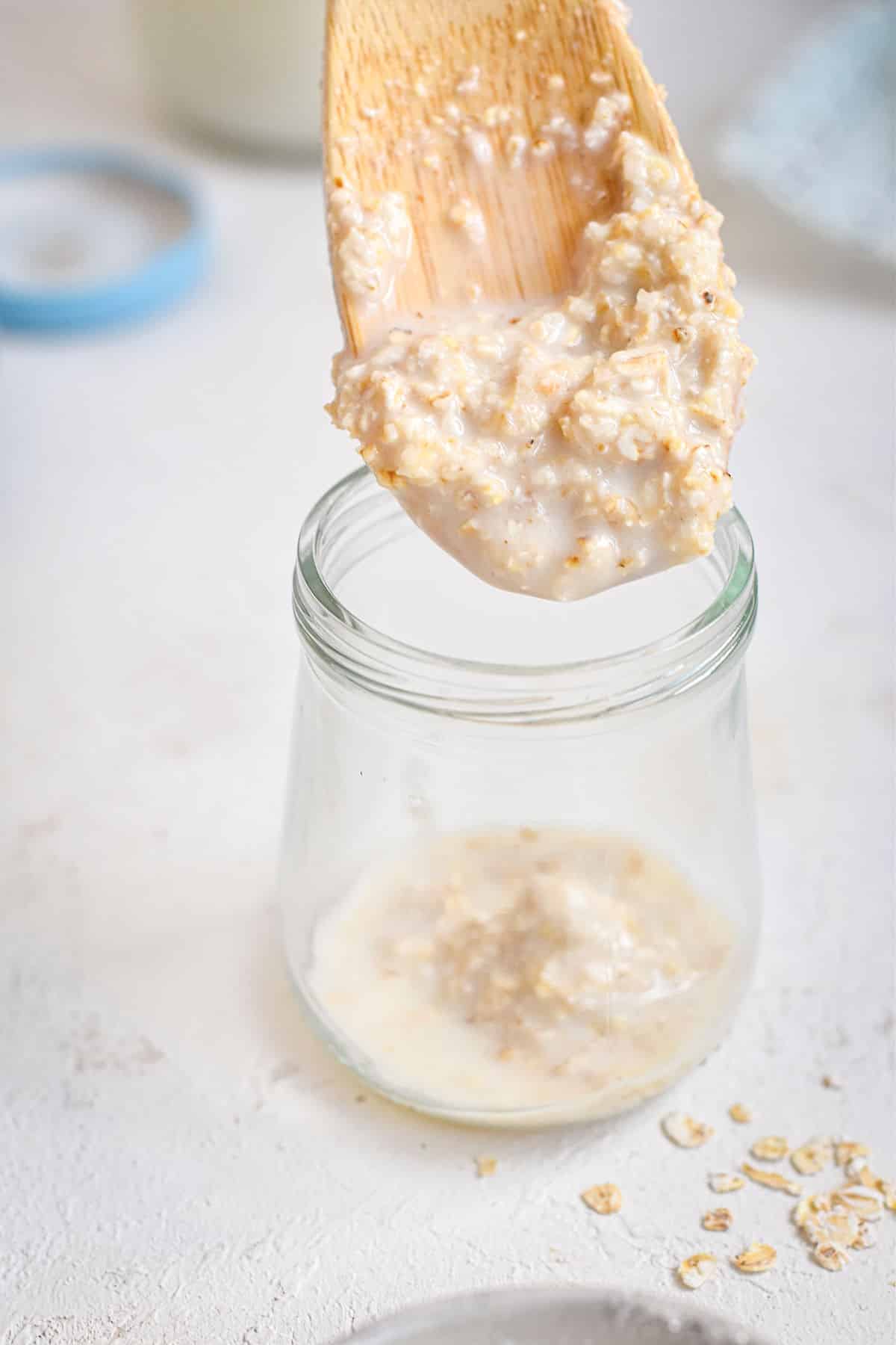 Oatmeal on a wooden spoon and in small jar.