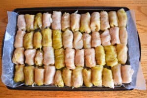 Unbaked cabbage rolls on sheet pan.