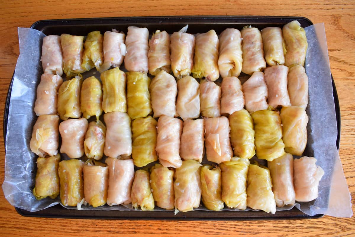 Unbaked cabbage rolls on sheet pan.
