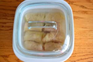 Unbaked cabbage rolls in casserole dish with lid.