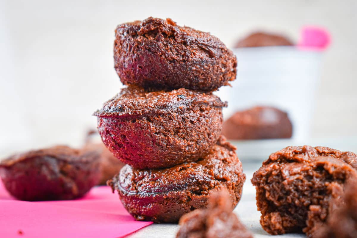 Brownie bites stacked on top of each other on pink napkin.