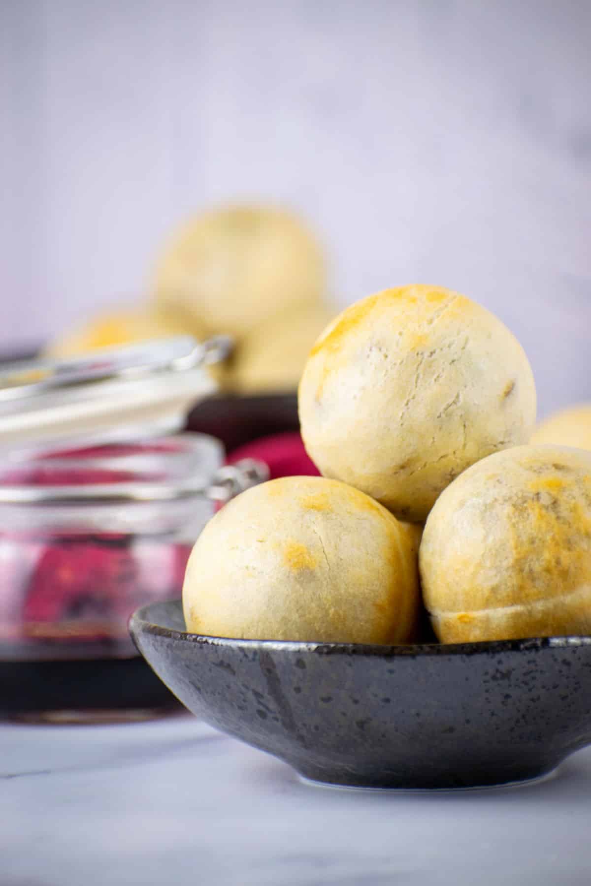 Chinese pork buns stacked in a black dish on light marble background.