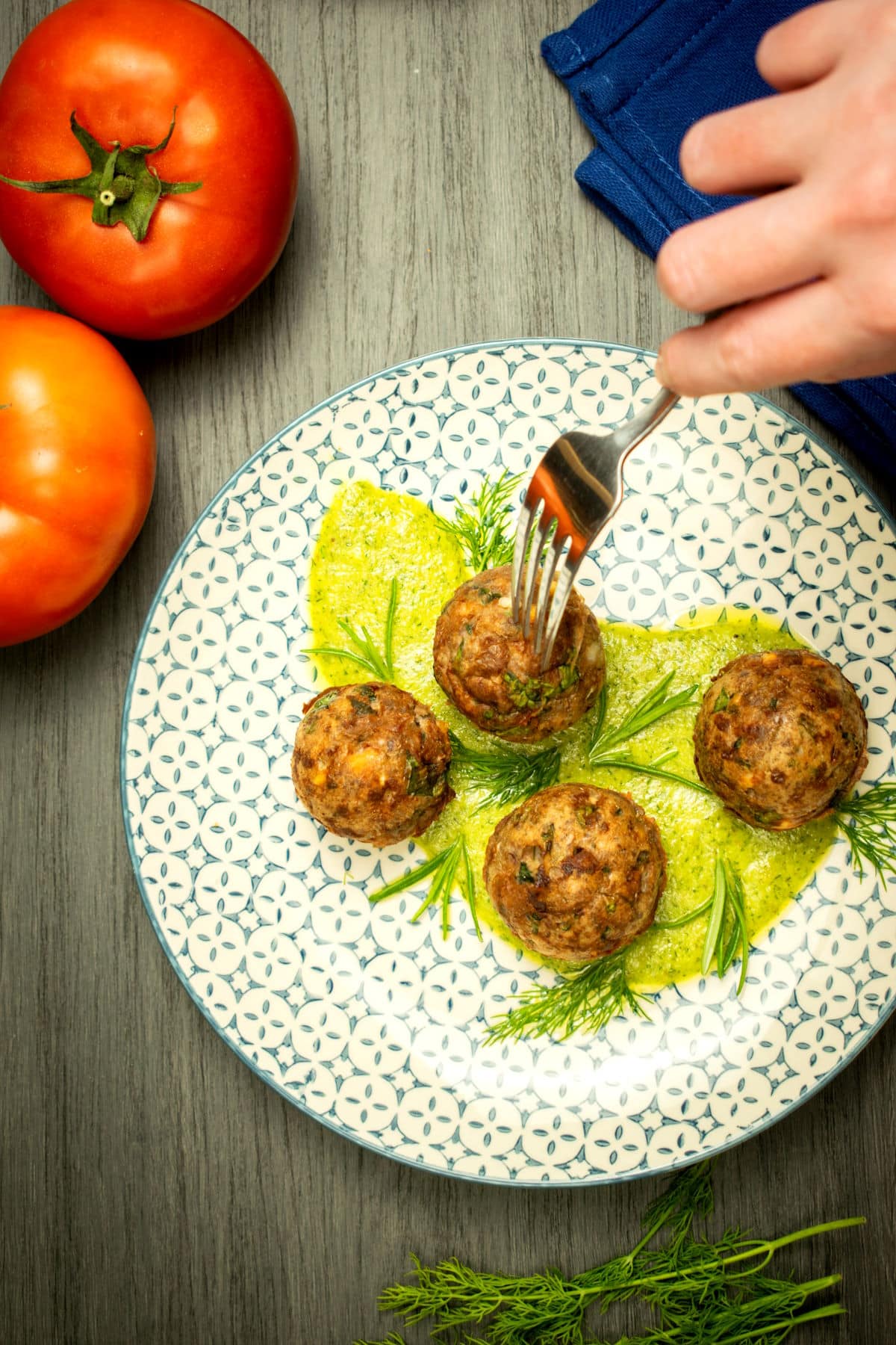 Mediterranean meatballs with dill sauce on decorative plate.