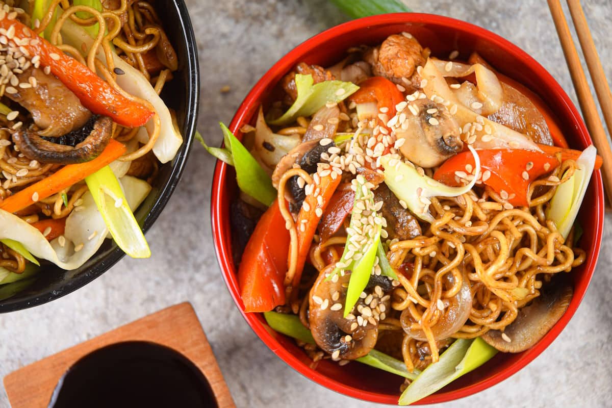Chicken lo mein noodles in red and black bowls.