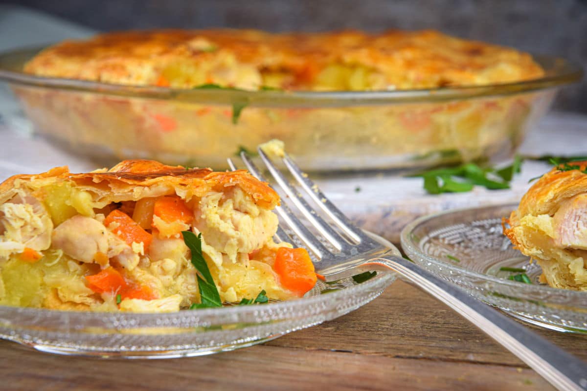 Chicken pasty pie slice on clear glass plate with a fork.