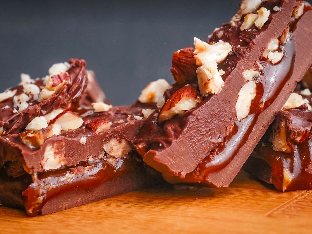 Chocolate caramel bars stacked on blue background.