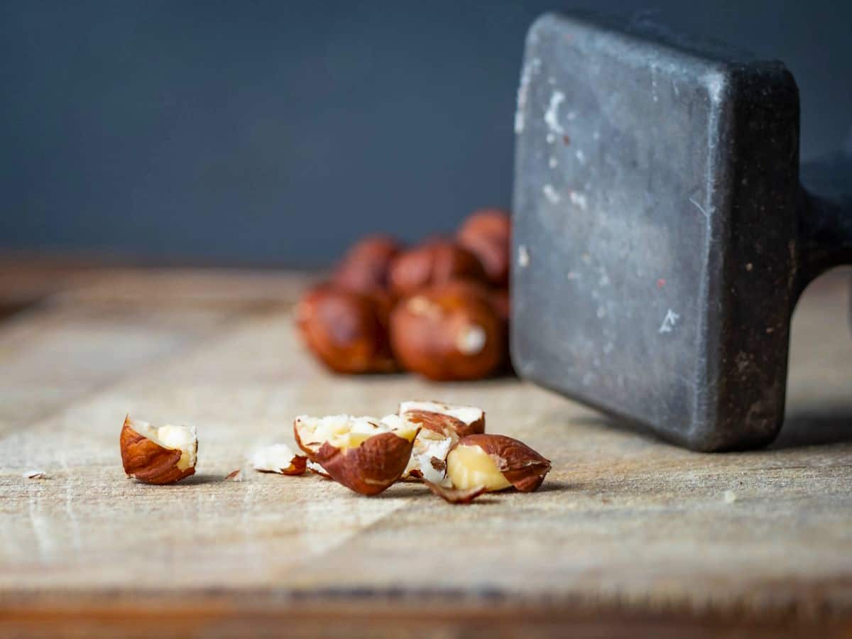 Hazelnuts and mallet on cutting board.