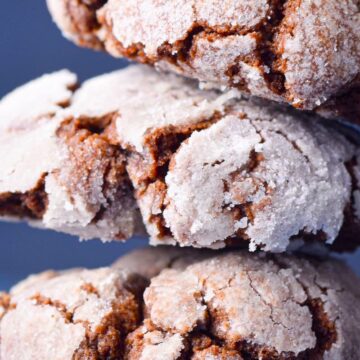 Chocolate crinkle cookies stacked on blue background.