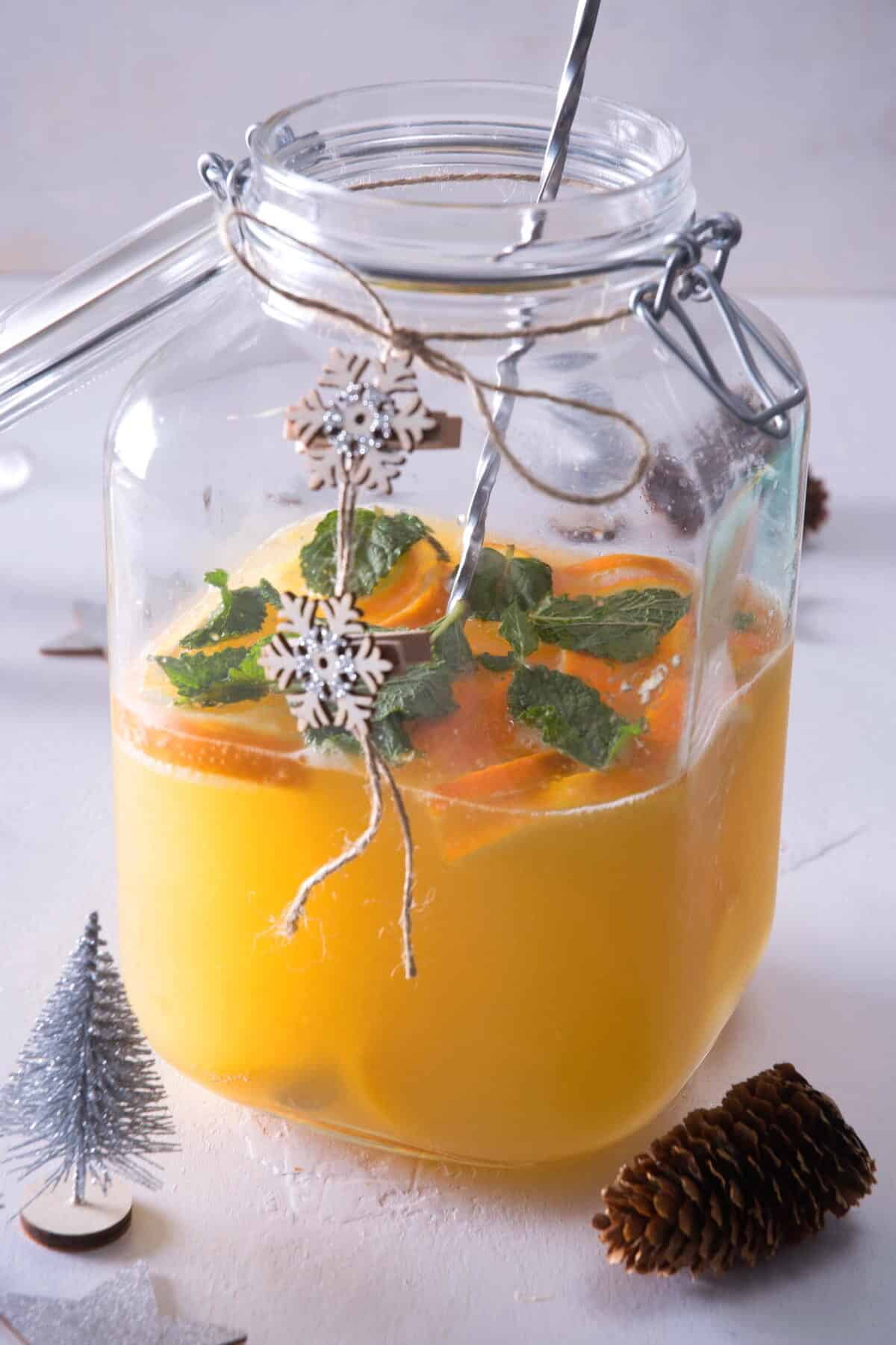 A large glass pitcher with Christmas punch and stirring stick.