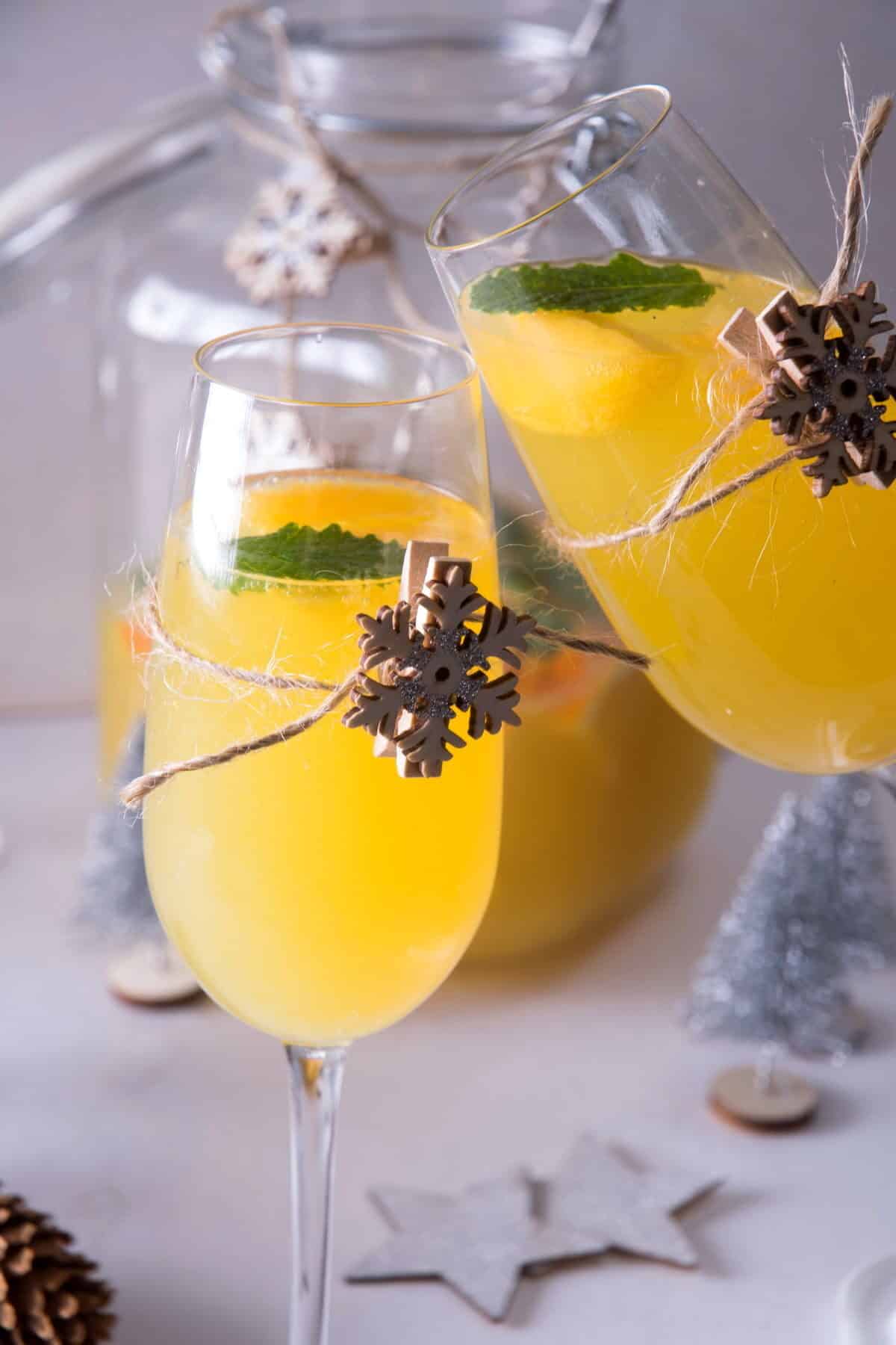 2 champagne glasses with Christmas punch, decorated with wooden snowflakes.