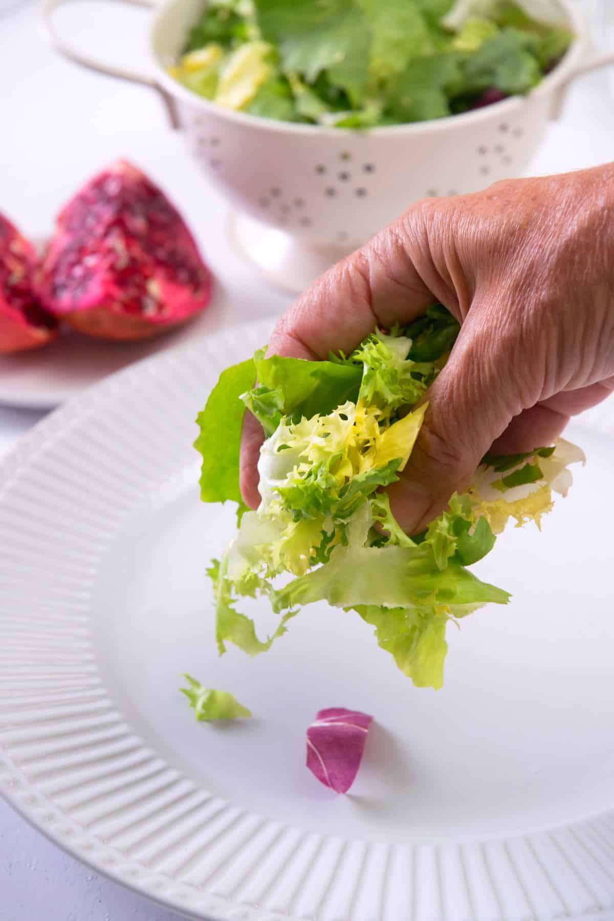 Greens getting placed on a white serving plate.