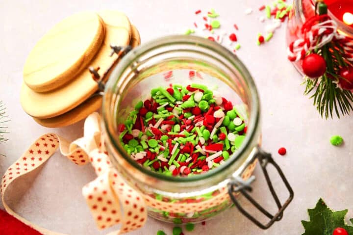 Christmas sprinkles in jar with holiday decorations.
