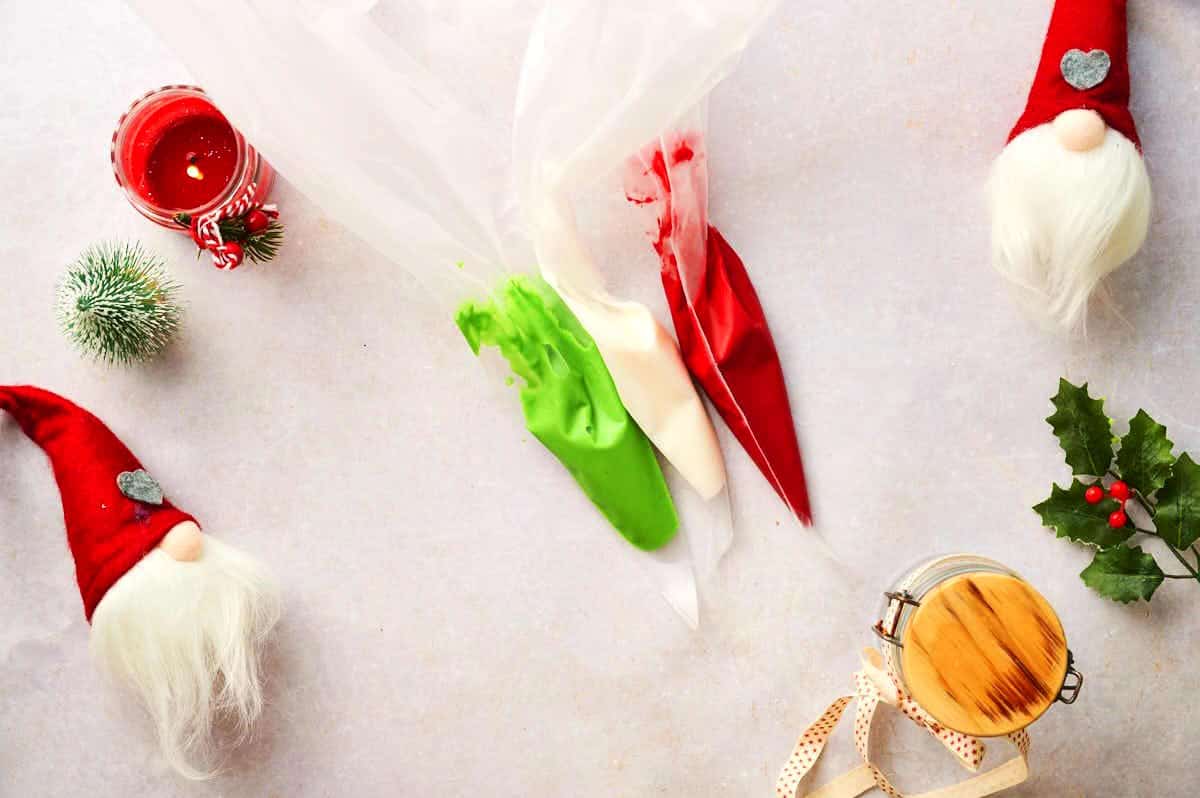 Red, green and white Christmas candy sprinkle mixtures in piping bags.