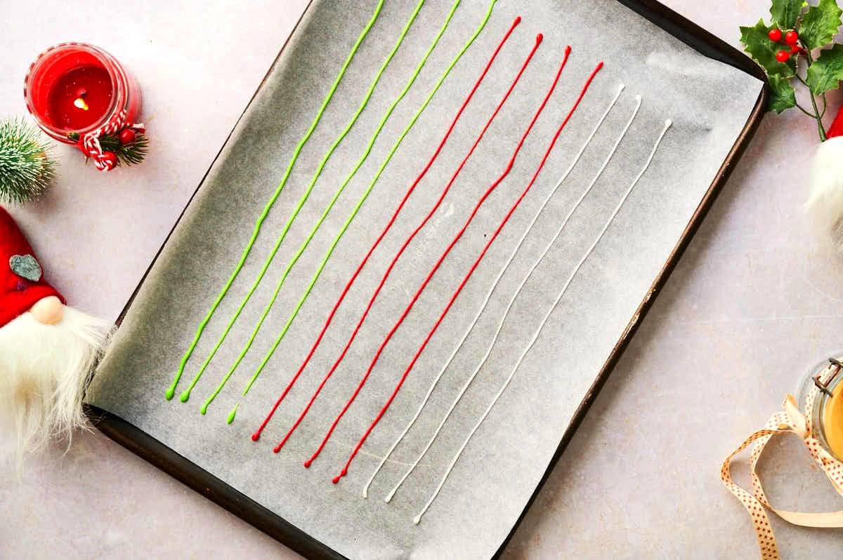Christmas candy sprinkle lines drying on wax paper lined baking sheet.
