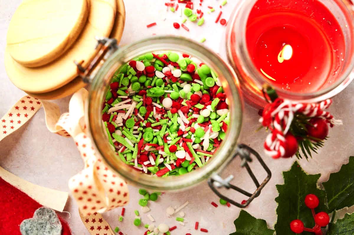 Christmas baking sprinkles in jar with candle on the side.