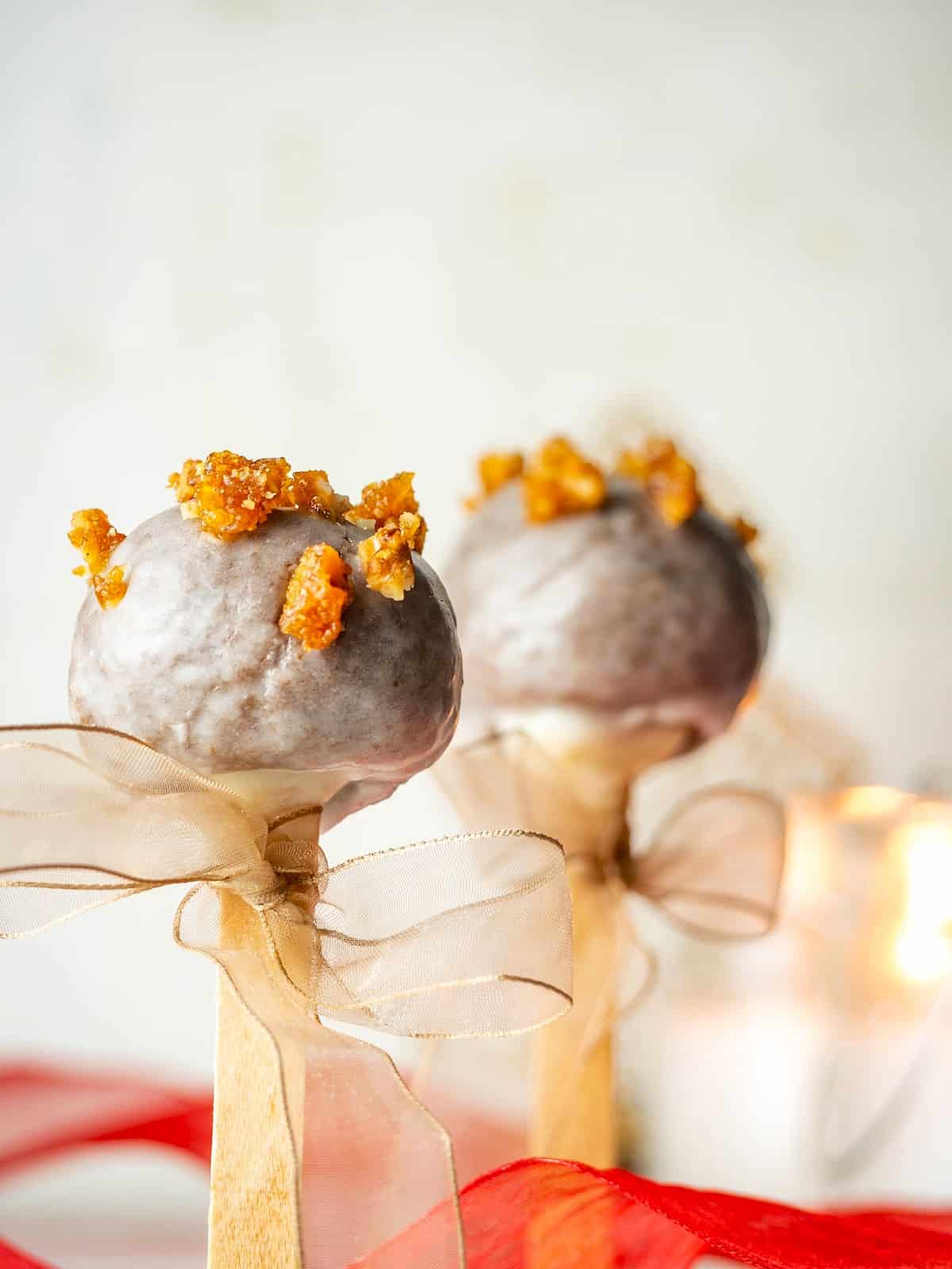 Christmas spice cake pops with beige ribbons tied around the treat stick.