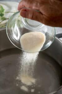 Gelatin powder pouring into a saucepan.