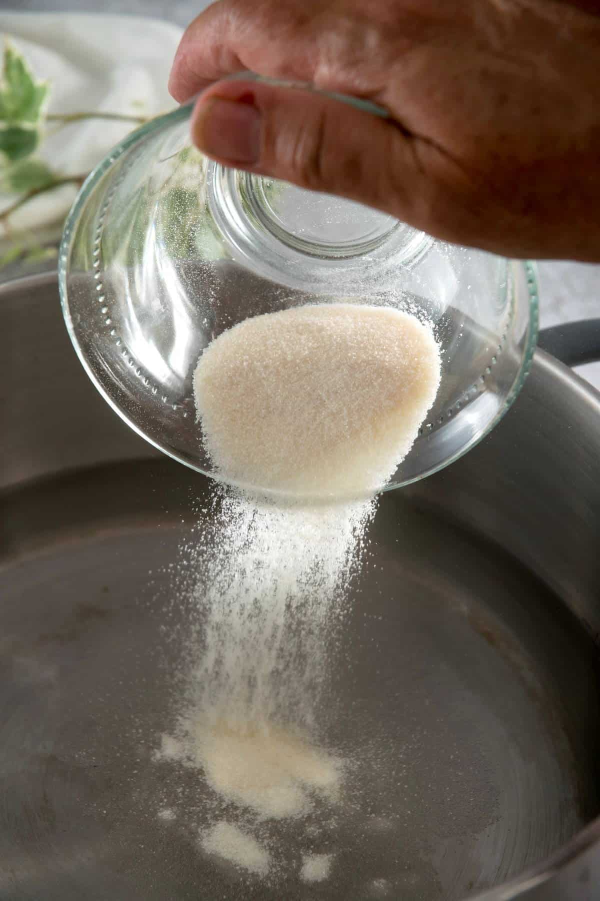 Gelatin powder pouring into a saucepan.