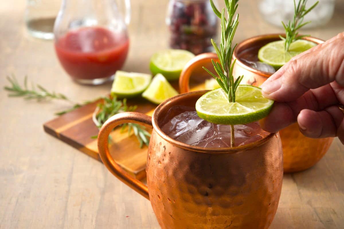 Lime slice and rosemary sprig in cranberry Moscow mule.