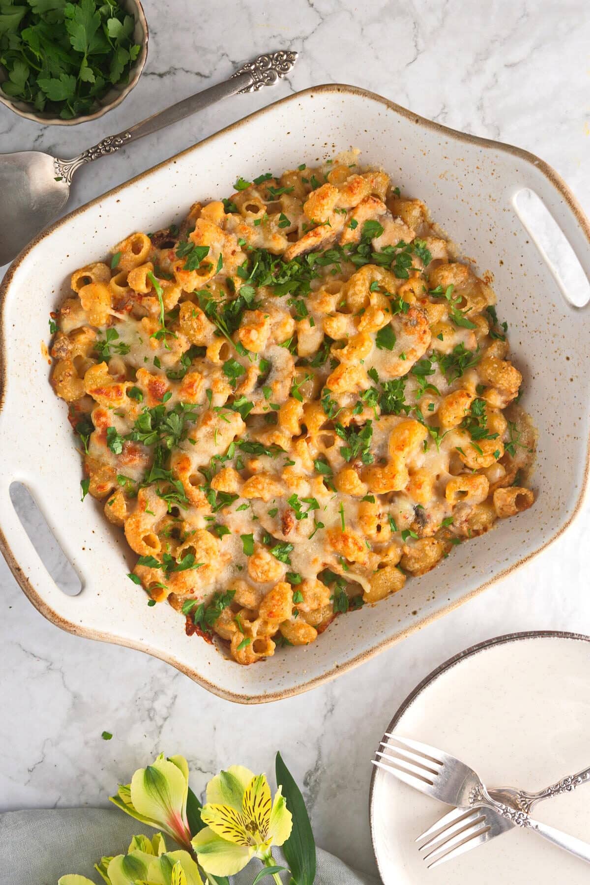 Tuna casserole in casserole dish with marble background. Plate with forks on the side.