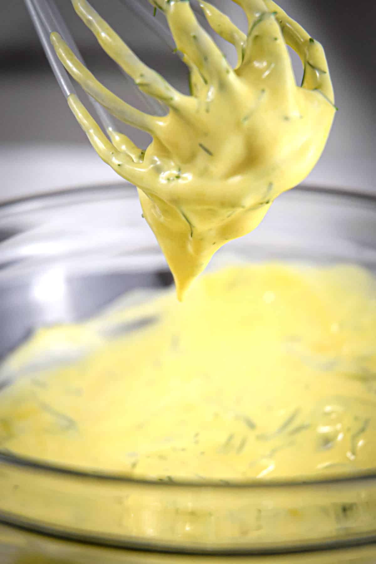 Dill dip in a bowl with a whisk.