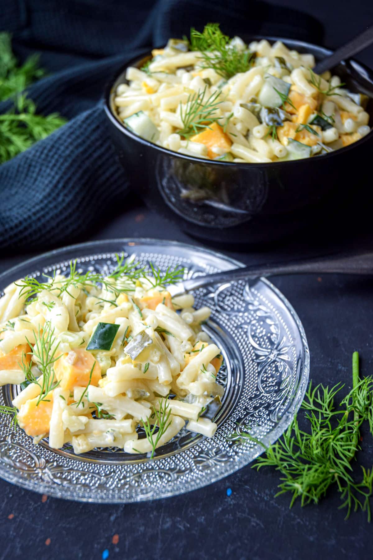 Dill pickle pasta salad with a fork on a clear glass plate.