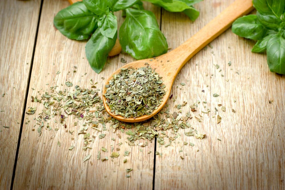 Dried Basil in a wooden spoon on wooden background.