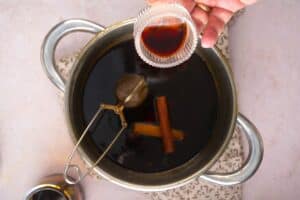 Vanilla extract in small jar over gingerbread syrup in saucepan.