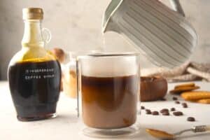 Milk pouring into mug with espresso and gingerbread syrup.