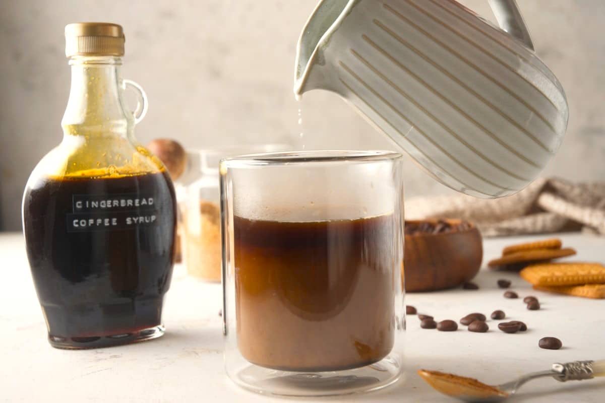 Milk pouring into mug with espresso and gingerbread syrup.
