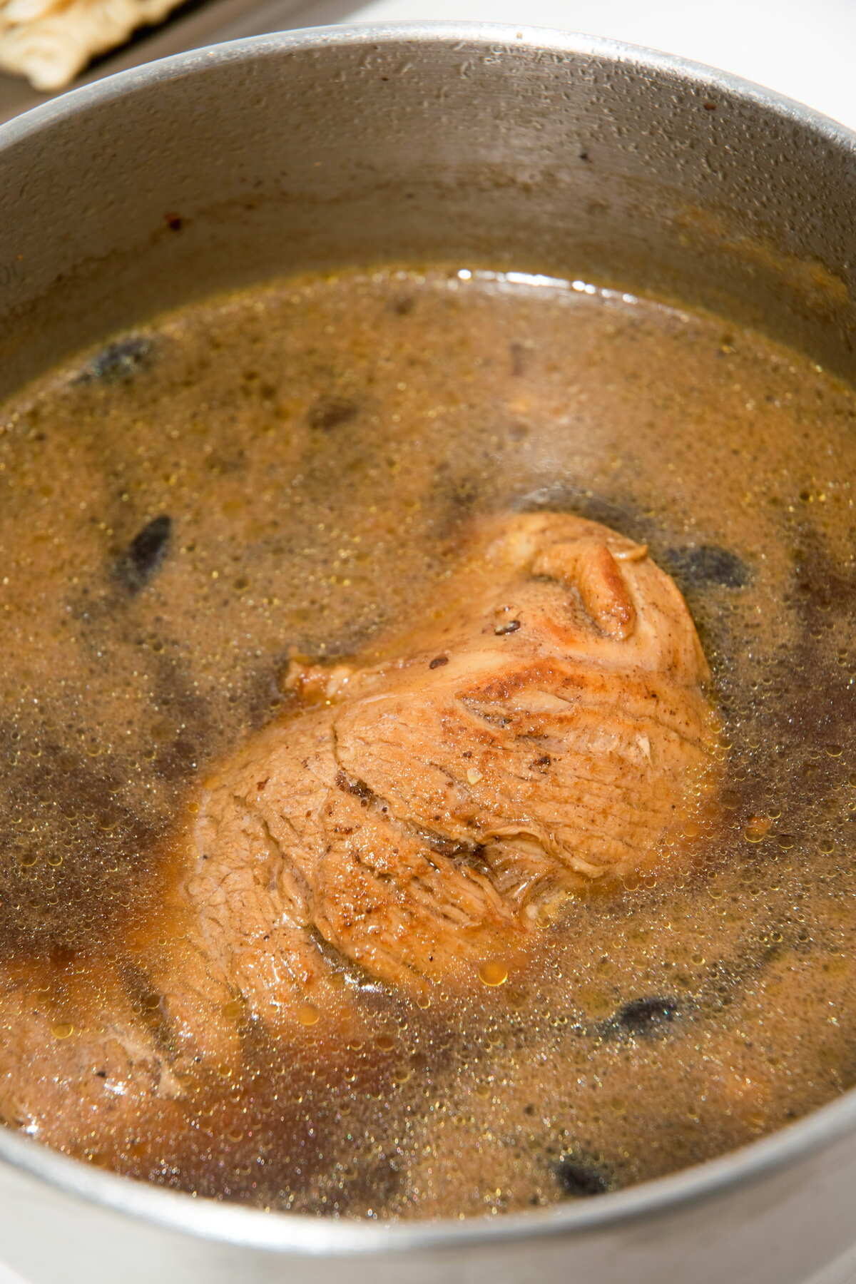 Broth with pork tenderloin in a large pot.