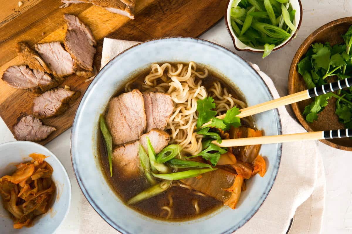 Kimchi ramen with pork slices and chopsticks in a bowl.