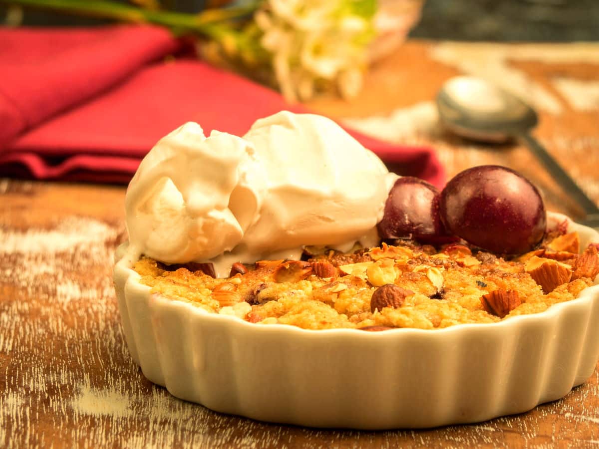 Plum crumble with vanilla ice cream in a tart dish.