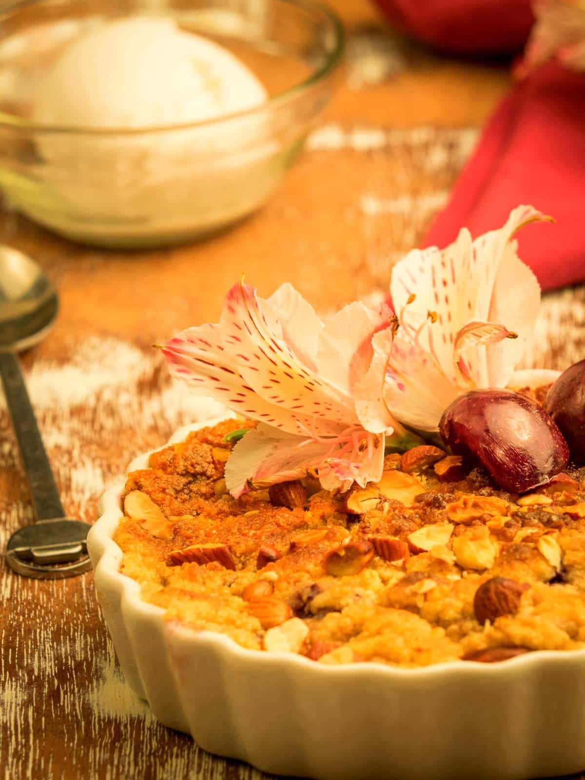 Plum crumble in a tart dish with flowers on top.