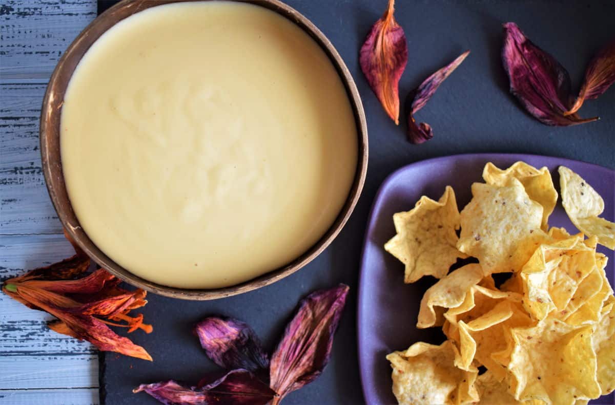 White cheddar nacho cheese sauce in a bowl, with tortilla chips on the side.