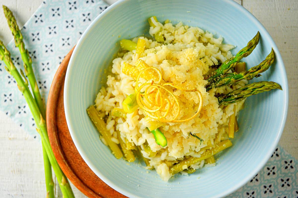 Risotto with lemon and asparagus in light blue bowl.