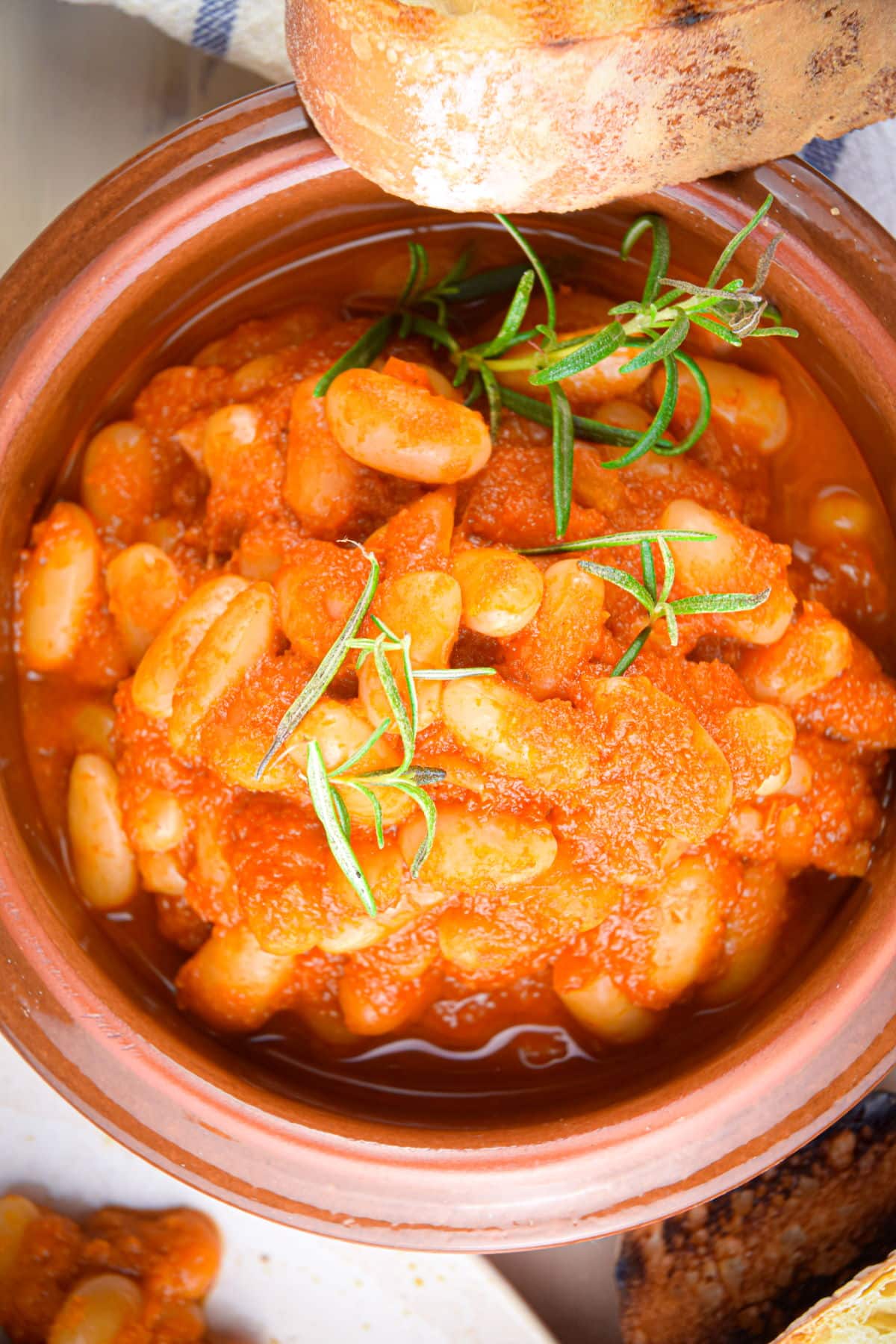 British baked beans in bowl with toast on the side and fresh rosemary.