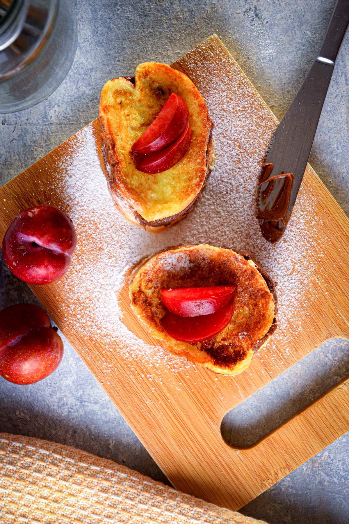 Electric skillet French toast stuffed with Nutella and topped with apples on cutting board.