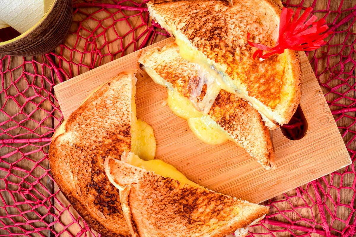 Electric Skillet Grilled Cheese 4 Electric skillet grilled cheese sandwiches on a cutting board. over a pink doiley.