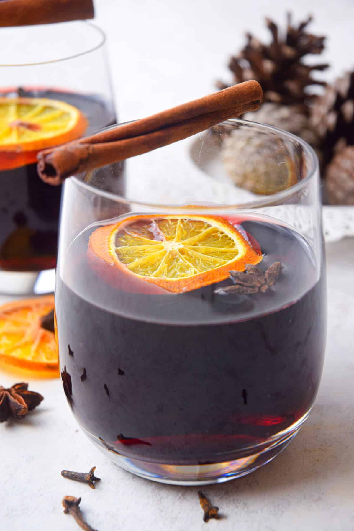 Mulled wine in a glass with an orange slice and cinnamon stick.