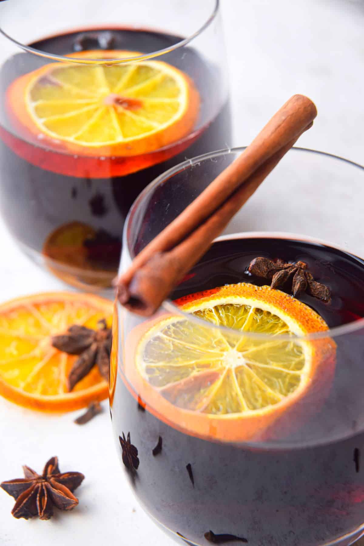 Mulled wine in a glass with an orange slice and cinnamon stick. Star anise on the side.