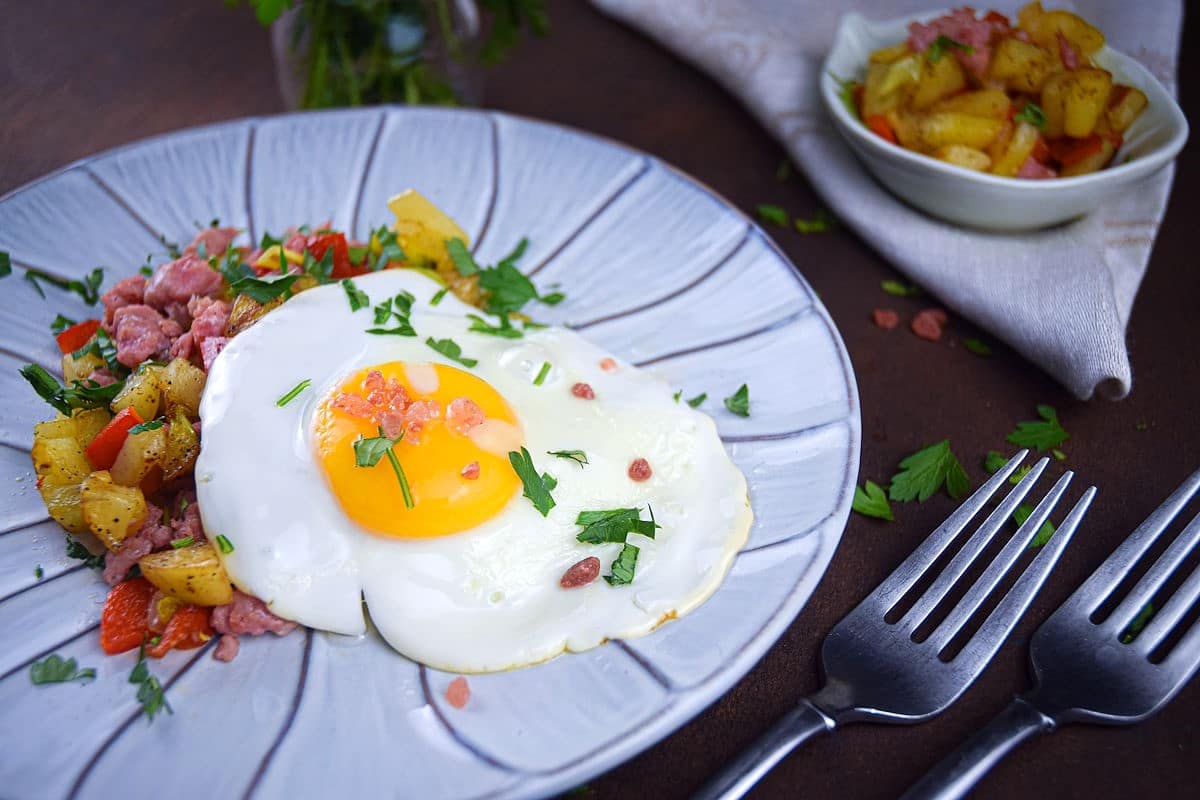 Egg and sausage hash on decorative plate with fresh parsley.