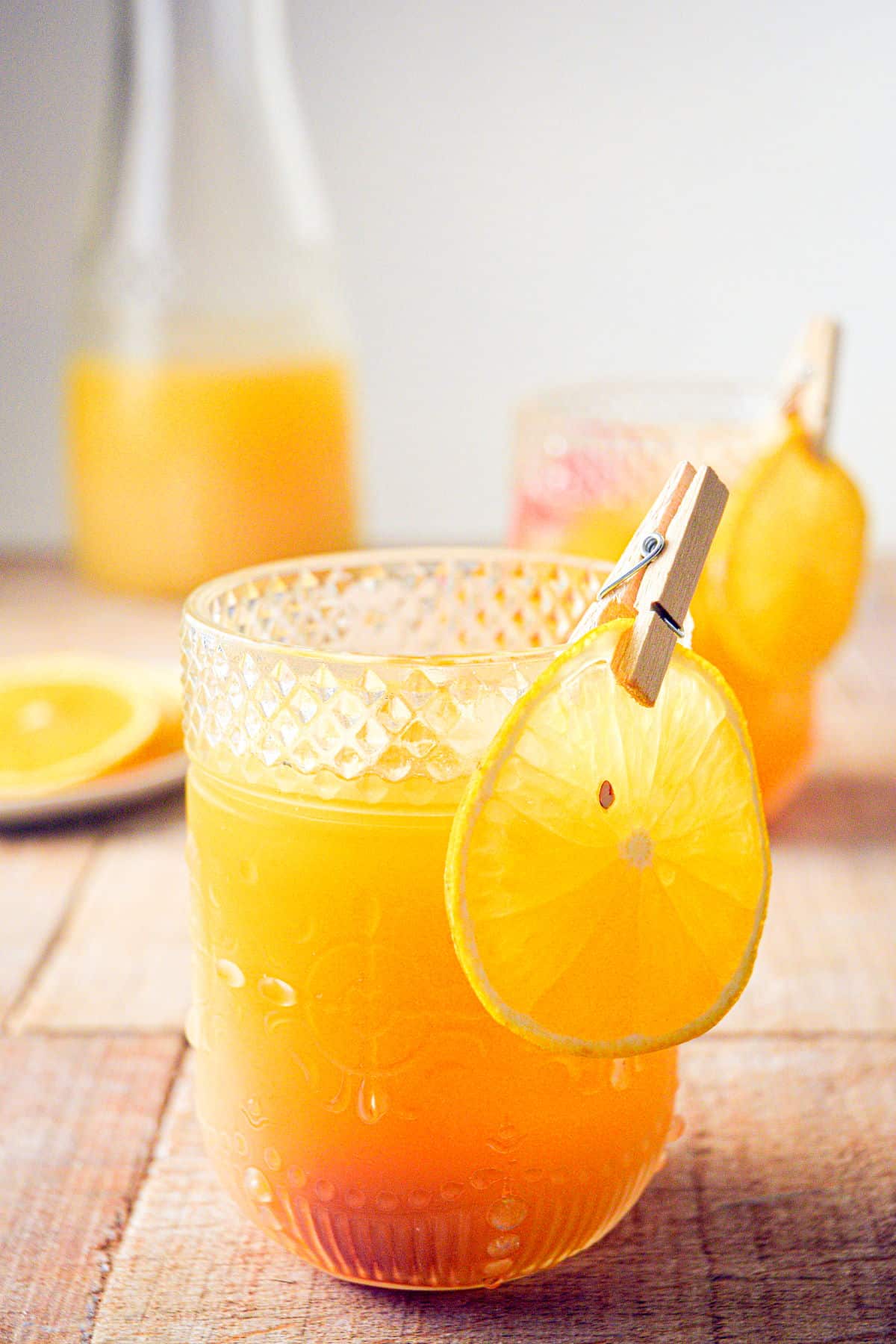 Pumpkin punch in glasses and a pitcher with orange slice garnish.