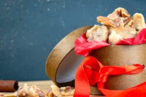 Praline pecans in gift box with red ribbon.