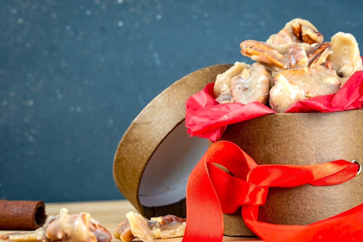 Praline pecans in gift box with red ribbon.
